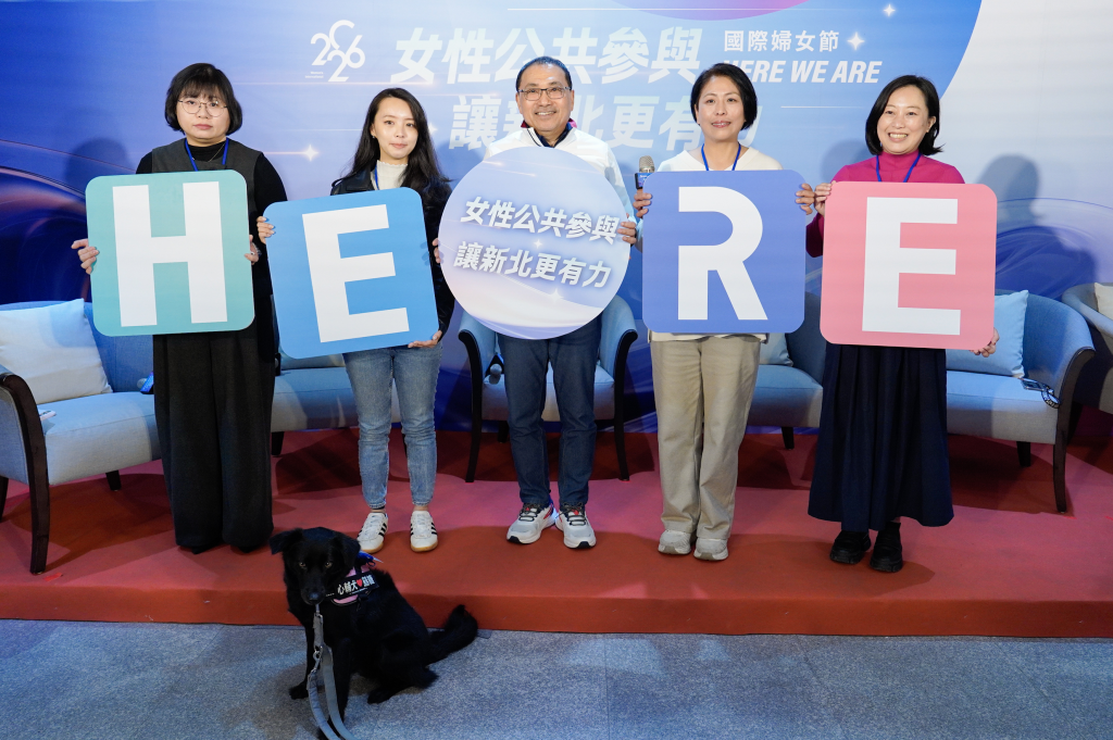 侯友宜市長與4位女力共同拼出「HERE」,象徵「女力就在這裡」,左起為弱勢家庭坐月子到宅服務員洪華聆、新北青農聯誼會副會長陳韻竹、三峽區有木里里長胡幸姍,以及台灣心輔犬培育團隊創辦人陳奕君與心輔犬「囍糖」 (新北社會局提供)